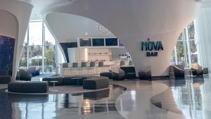 Futuristic Nova Bar with sleek white architecture, curved seating areas, and a modern bar backed by floor-to-ceiling windows.