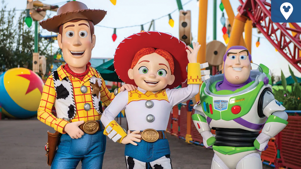 Woody, Jessie, and Buzz Lightyear posing together in Toy Story Land with colorful rides in the background