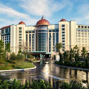 Exterior of Universal Helios Grand Hotel featuring domed rooftops, grand entrance, and surrounding palm trees under a blue sky.