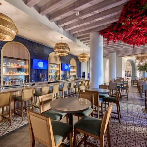 Flora Taverna restaurant at Universal Helios Grand Hotel, featuring a bar, modern décor, and floral ceiling accents.