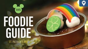 A dessert with a rainbow and clover decoration, with text overlay reading "Eats Foodie Guide St. Patrick's Day."