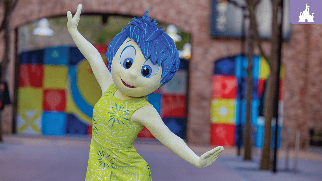 A character with blue hair and a bright yellow dress strikes a cheerful pose in a colorful outdoor setting.
