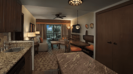 walt-disney-world-resort-animal-kingdom-lodge-jambo-one-bedroom-villa A spacious hotel room featuring a kitchenette, dining area, cozy seating, and a balcony with natural light and decorative lamps.