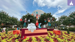 A vibrant display with colorful decorations and flowers, featuring tall figures, marking a food and wine festival at an outdoor venue.