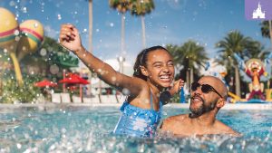 Father and daughter enjoying a sunny day swimming at a Walt Disney World Resort pool, surrounded by colorful decor and palm trees.