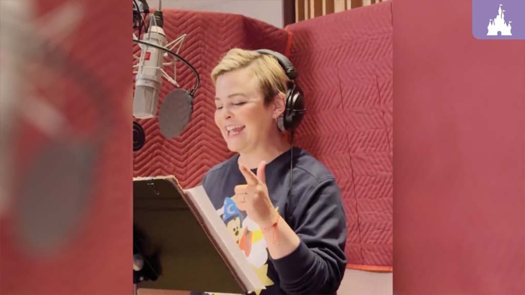 Actress recording voiceover in a sound booth, wearing headphones and reading from a script. A professional microphone is positioned in front of her, and the booth is lined with red acoustic panels.