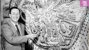 Walt Disney pointing to an early black-and-white concept map of Disneyland, showcasing the original park layout.